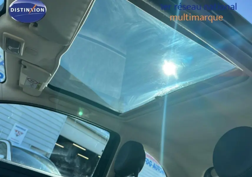 Vue intérieure du toit ouvrant électrique de la Fiat 500 noire, avec lumière du soleil traversant le vitrage panoramique.