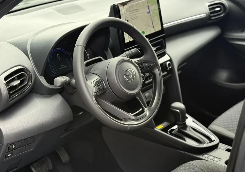 Vue intérieure côté conducteur de la Toyota Yaris Cross 1.5 Hybrid 116 Design avec volant cuir et écran tactile central.