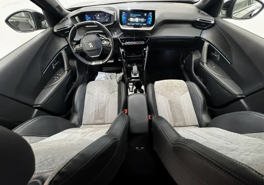 Vue intérieure avant du Peugeot E-2008 électrique GT Pack 2021, avec sièges bi-matière gris et noir et tableau de bord numérique.