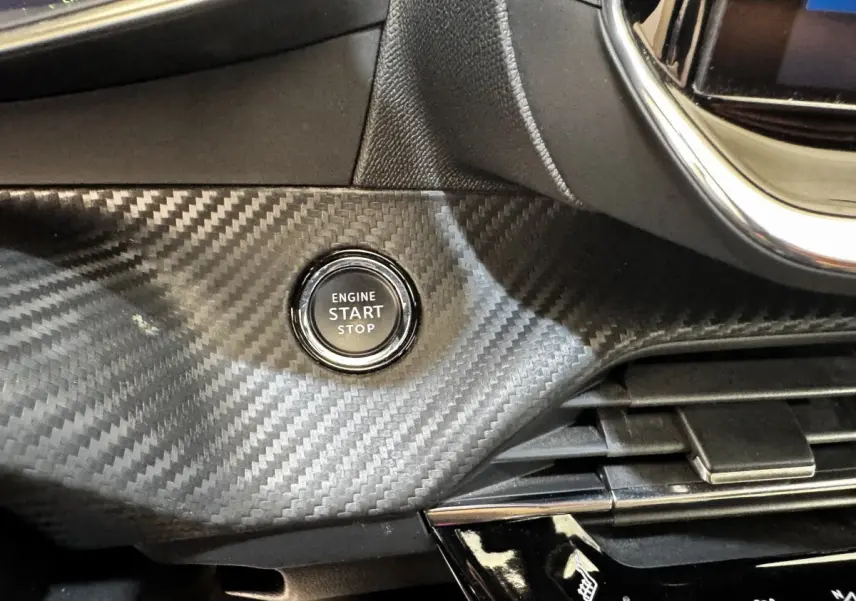 Bouton démarrage moteur sur tableau de bord noir effet carbone du Peugeot E-2008 électrique GT Pack.