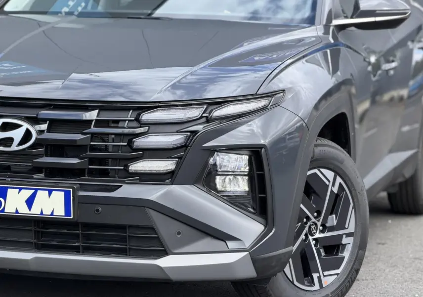 Gros plan sur l’avant droit du Hyundai Tucson Ecotronic Gray 2026, mettant en valeur ses phares bi-LED et jantes alliage 17 pouces.