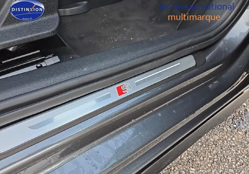 Gros plan sur le seuil de porte avec logo S illuminé de l'Audi A3 Sportback gris Daytona côté gauche.