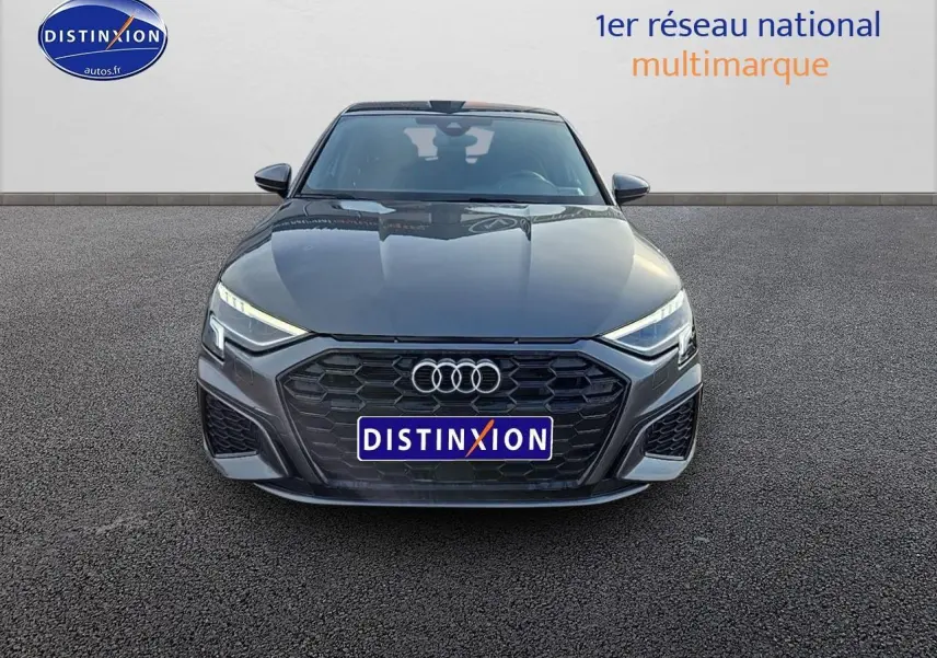 Audi A3 Sportback 45 TFSI e gris Daytona vue de face, calandre noire et phares LED allumés.