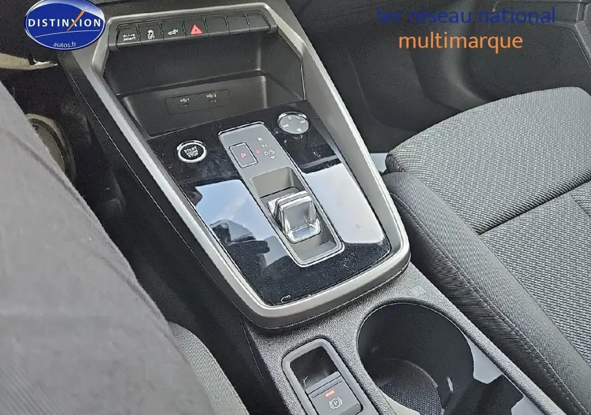 Gros plan sur la console centrale noire brillante avec levier de boîte automatique et siège tissu gris de l'Audi A3 Sportback 2024
