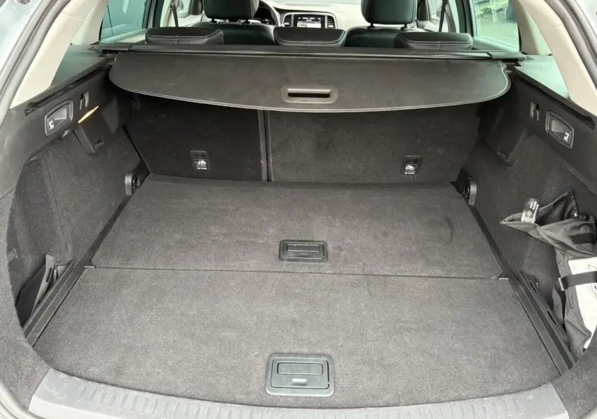 Coffre spacieux et vide de la Renault Mégane Break 2024 gris Highland, vue arrière ouverte avec cache-bagages déployé.