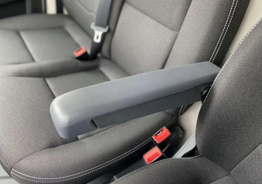 Gros plan sur l'accoudoir central relevable et la sellerie noire avec surpiqûres blanches du Citroën Jumper 2025.