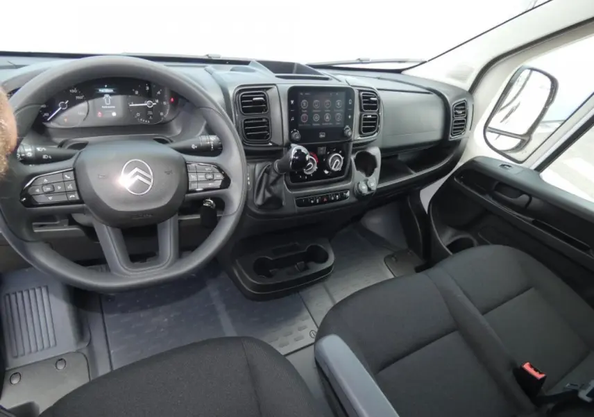 Vue intérieure côté conducteur du Citroën Jumper 2025, tableau de bord noir avec écran tactile central et volant multifonction.