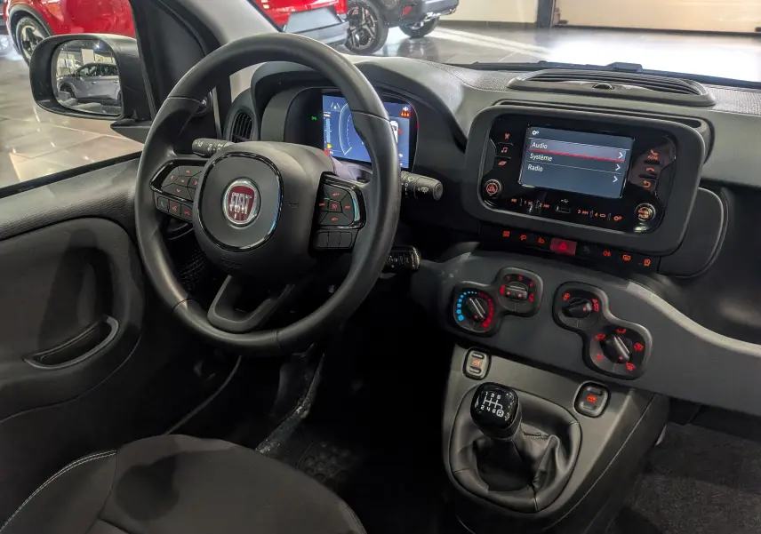 Vue intérieure côté conducteur de la Fiat Panda blanche Gelato 2025, avec volant multifonction et tableau de bord numérique.