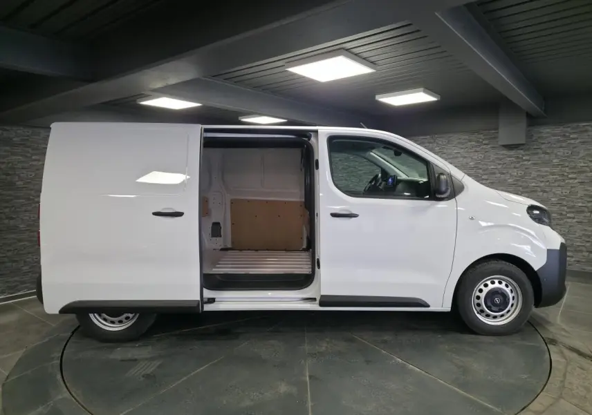 Vue latérale droite d'un Opel Vivaro blanc 2025 avec porte coulissante ouverte montrant l'espace de chargement vide.