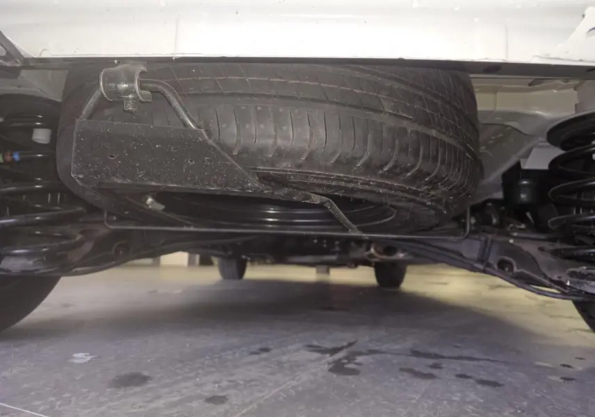 Vue en contre-plongée sous un Opel Vivaro blanc montrant la roue de secours montée sous le châssis.