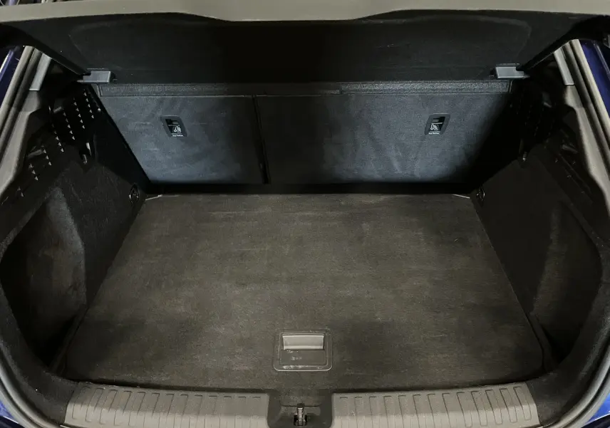 Coffre ouvert vu de face d'une Audi A3 Sportback bleu métallisé, montrant un espace de chargement propre et noir.