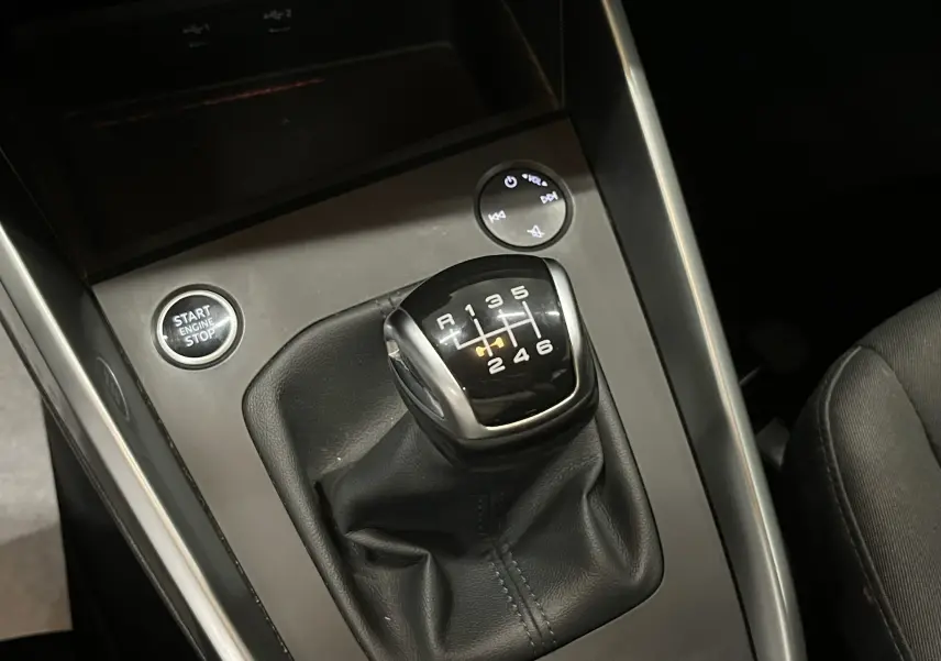 Gros plan sur le levier de vitesses manuel noir de l’Audi A3 Sportback 30 TFSI avec bouton démarrage, intérieur tissu noir.