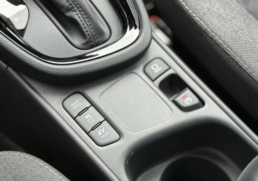 Gros plan sur la console centrale de la Toyota Yaris Cross 1.5 Hybrid 116 Design avec commandes de mode de conduite et frein électrique.