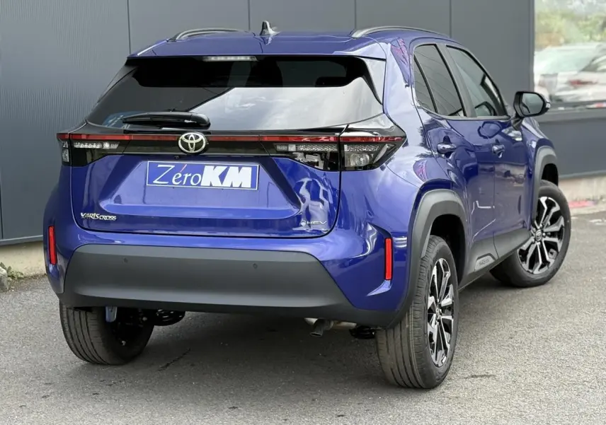 Vue 3/4 arrière droite d'une Toyota Yaris Cross 1.5 Hybrid bleu Genievre avec feux arrière LED et jantes alliage noires.