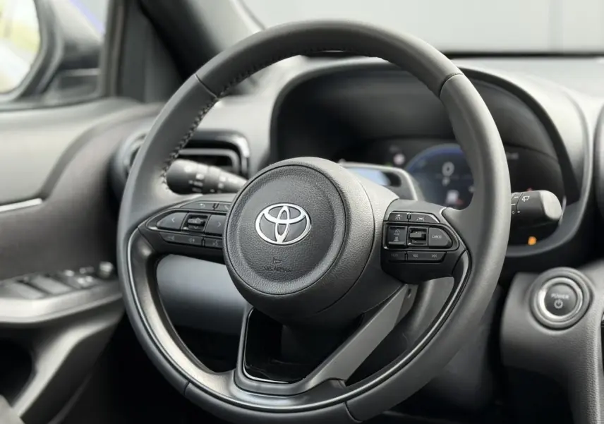 Vue rapprochée du volant cuir noir de la Toyota Yaris Cross 2026 avec commandes intégrées et tableau de bord flou.