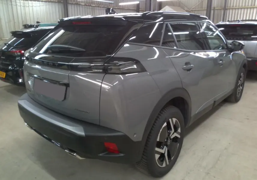 Vue 3/4 arrière droite d'un Peugeot 2008 gris selenium avec barres de toit noires et vitres teintées.