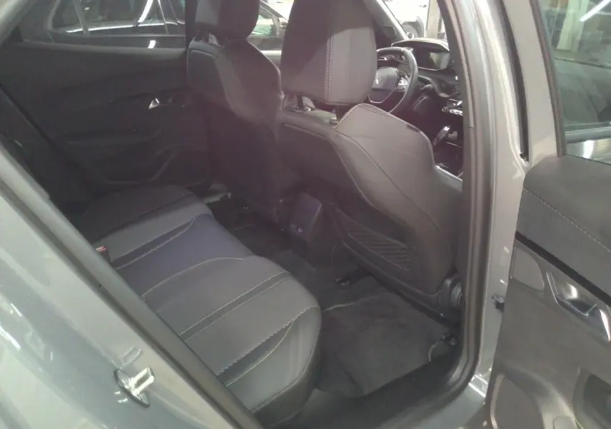 Vue intérieure arrière côté gauche du Peugeot 2008 1.2 Hybrid 145ch GT gris Selenium, sièges en cuir noir avec surpiqûres claires.