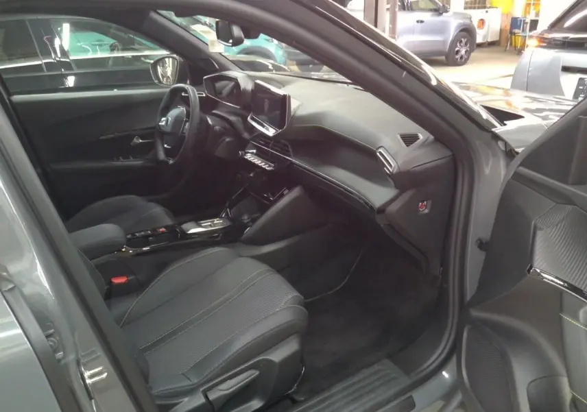 Intérieur avant droit du Peugeot 2008 gris selenium 2025, avec tableau de bord moderne et sièges tissu noir.