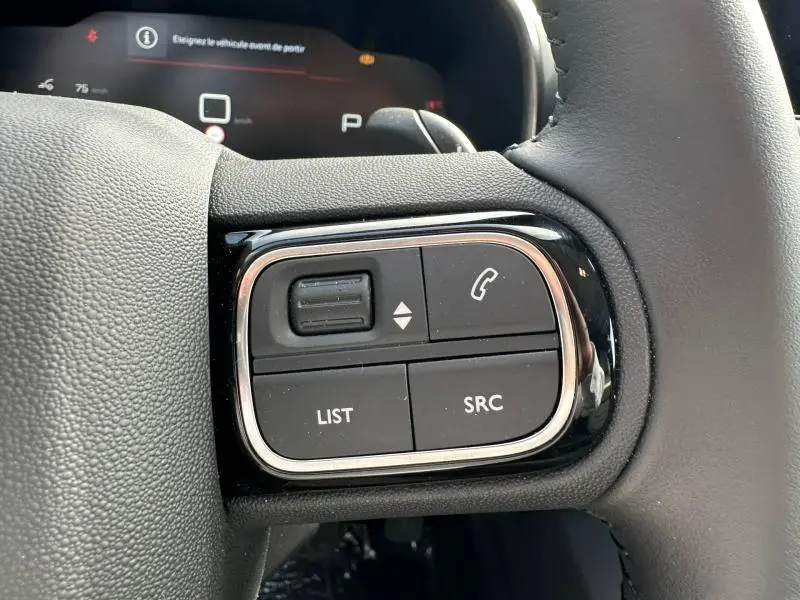 Gros plan sur les commandes au volant côté gauche du Citroën C5 Aircross 2025 noir Perla Nera, avec boutons multifonctions.