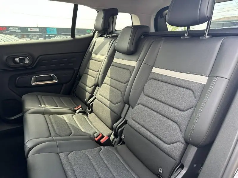 Vue intérieure des sièges arrière du Citroën C5 Aircross 2025 en cuir et tissu gris, avec appuie-têtes et ceinture de sécurité visibles.