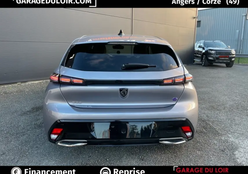 Vue arrière d'une Peugeot 308 gris foncé 2024 avec feux LED allumés et double sortie d'échappement chromée.