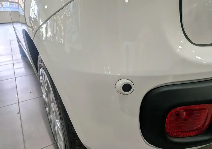 Gros plan sur l’aile arrière droite blanche Gelato de la Fiat Panda 1.0 70 CH Hybrid City avec feu arrière et capteur de stationnement.