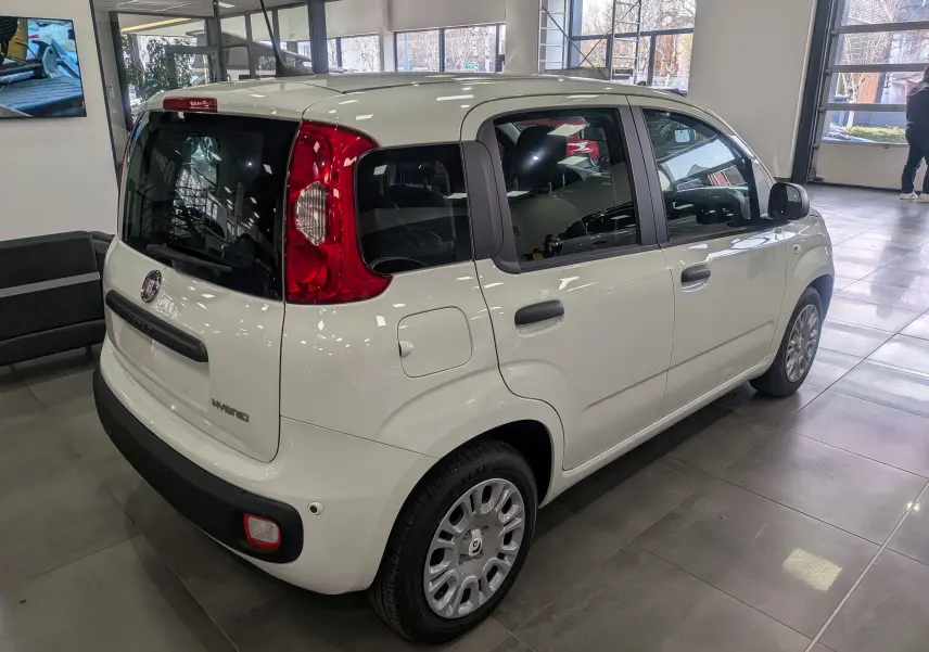 Vue 3/4 arrière droite d'une Fiat Panda 1.0 Hybrid City blanche Gelato en showroom avec feux arrière rouges distinctifs.
