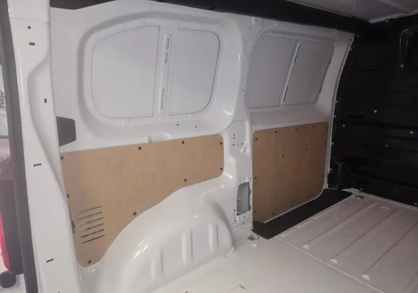 Vue intérieure du coffre arrière blanc de l'Opel Vivaro 2025, avec panneaux de protection en bois clair sur les parois.