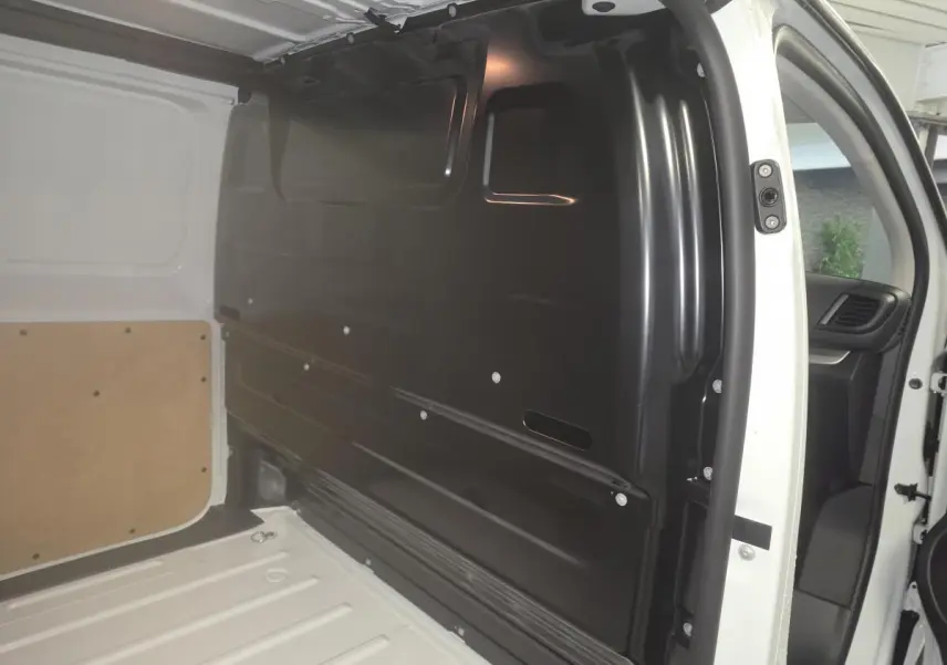 Vue intérieure côté droit du compartiment de chargement blanc de l'Opel Vivaro 2025 avec cloison noire tôlée.