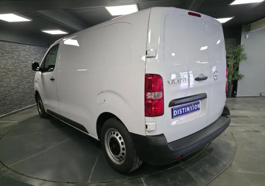 Vue 3/4 arrière droite d’un Opel Vivaro blanc avec portes arrière tôlées et roues tôles grises en intérieur showroom.