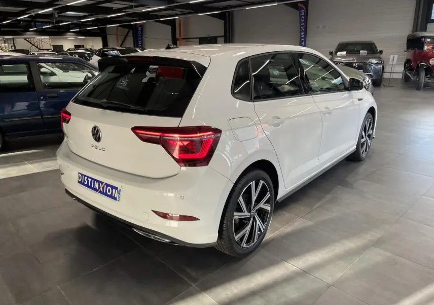Vue 3/4 arrière droite d'une Volkswagen Polo blanche 2024 finition R-Line avec jantes alliage et feux LED distinctifs.