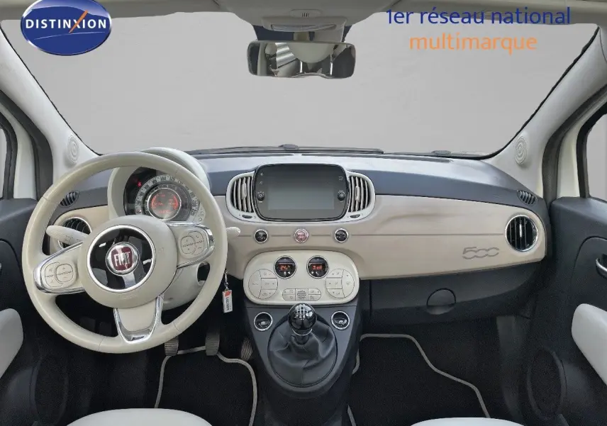 Intérieur clair de la Fiat 500 1.0 Hybrid 2022, vue frontale du tableau de bord avec volant beige et console centrale moderne.