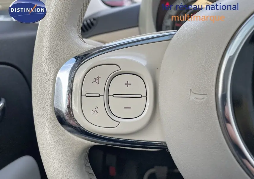 Gros plan sur les commandes blanches du volant cuir clair d'une FIAT 500 blanche, version 1.0 Hybrid 70CH DolceVita.