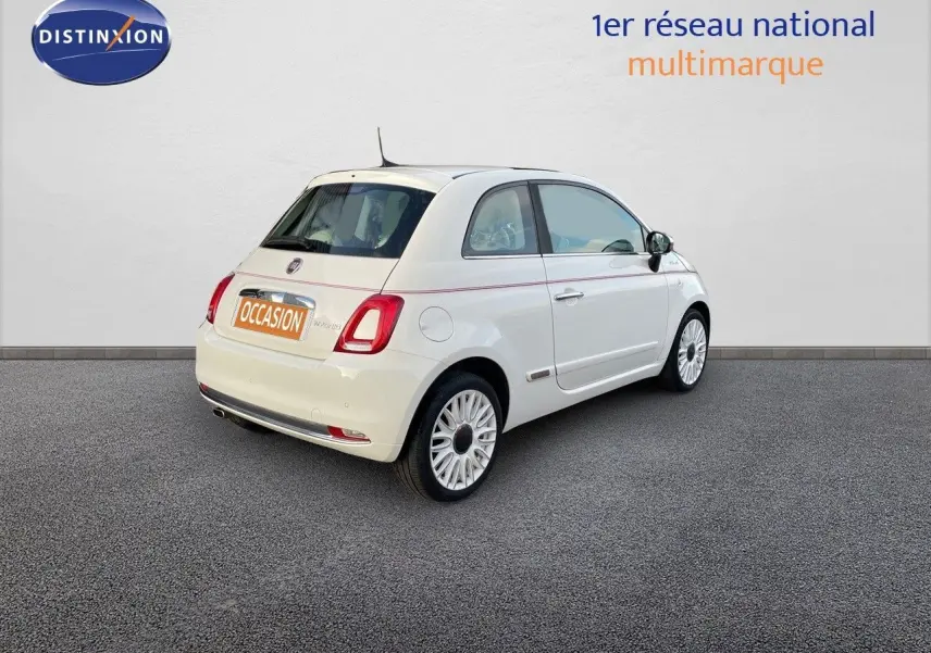 Vue 3/4 arrière droite d'une FIAT 500 blanche 2022 version 1.0 Hybrid DolceVita avec jantes biton et toit blanc.
