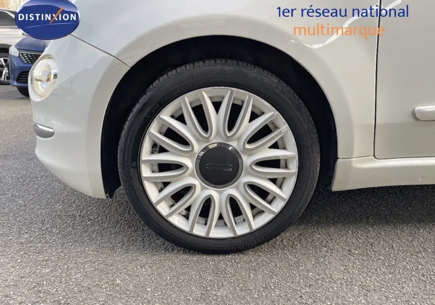 Gros plan sur la roue avant gauche blanche d'une FIAT 500 1.0 HYBRID 70CH DOLCEVITA de 2022, avec jante multibranches.