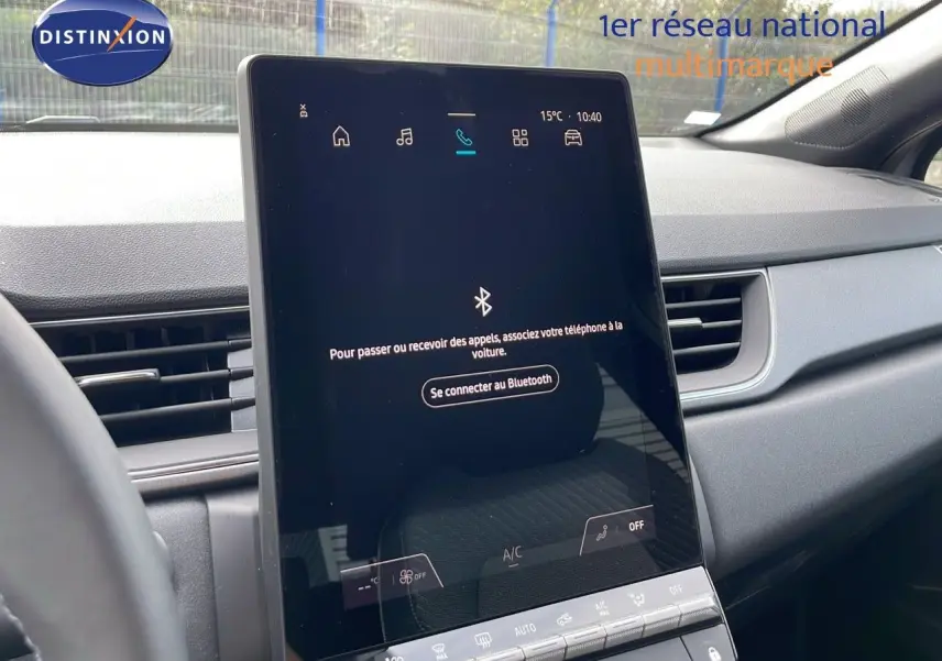 Écran tactile central allumé dans l'habitacle gris du Renault Captur E-Tech Hybrid 2025, vue de face côté conducteur.