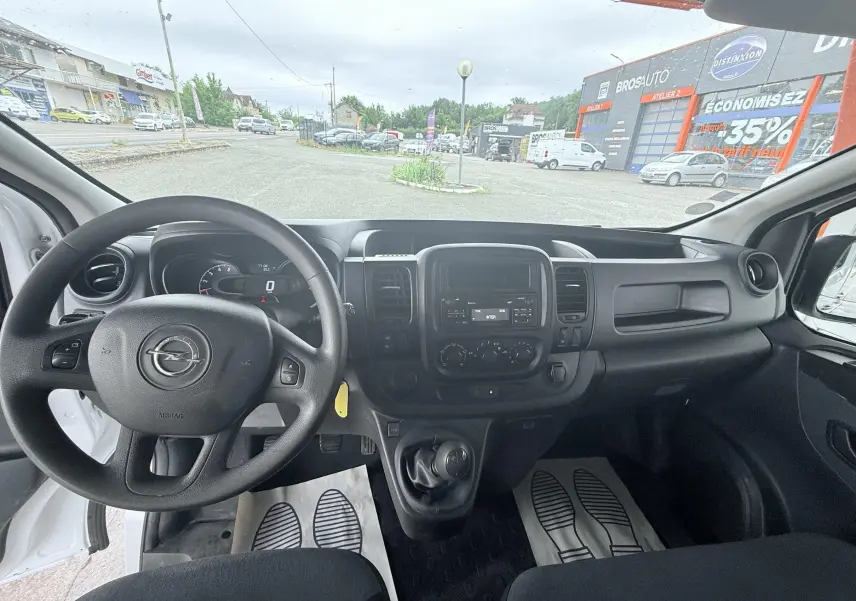 Vue intérieure avant de l'Opel Vivaro blanc 2018, montrant le volant, tableau de bord et levier de vitesse manuel.
