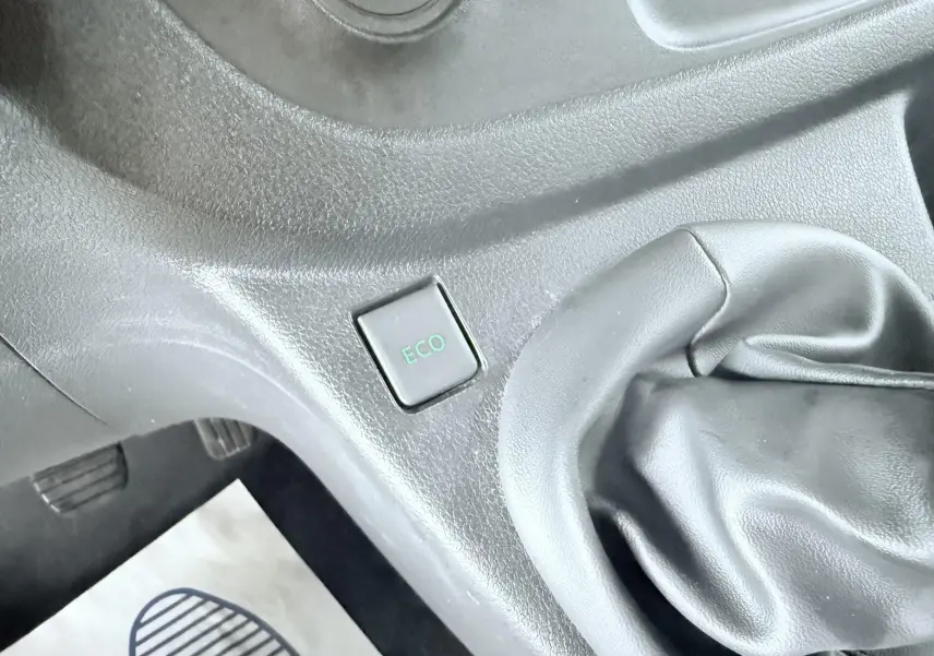 Gros plan intérieur sur le levier de vitesses manuel et le bouton ECO du tableau de bord noir du Opel Vivaro blanc.