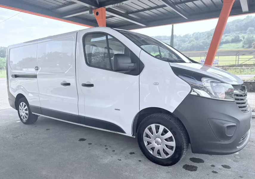 Vue 3/4 avant droit d’un utilitaire Opel Vivaro blanc avec pare-chocs noir sous un abri métallique.
