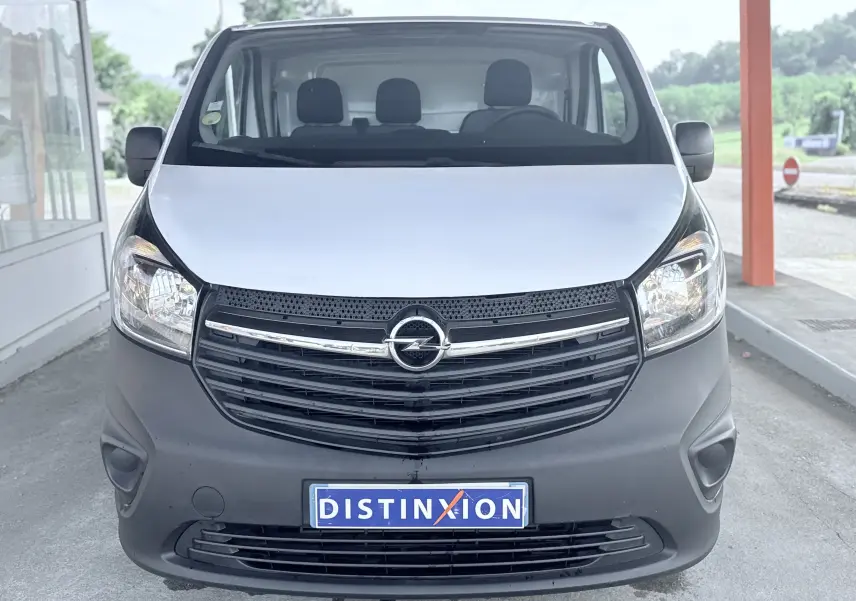 Vue avant d’un Opel Vivaro blanc avec calandre noire et plaque d’immatriculation Distinxion visible.
