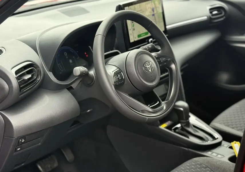 Vue intérieure côté conducteur du Toyota Yaris Cross 1.5 Hybrid 2026, volant cuir et écran tactile central visibles.
