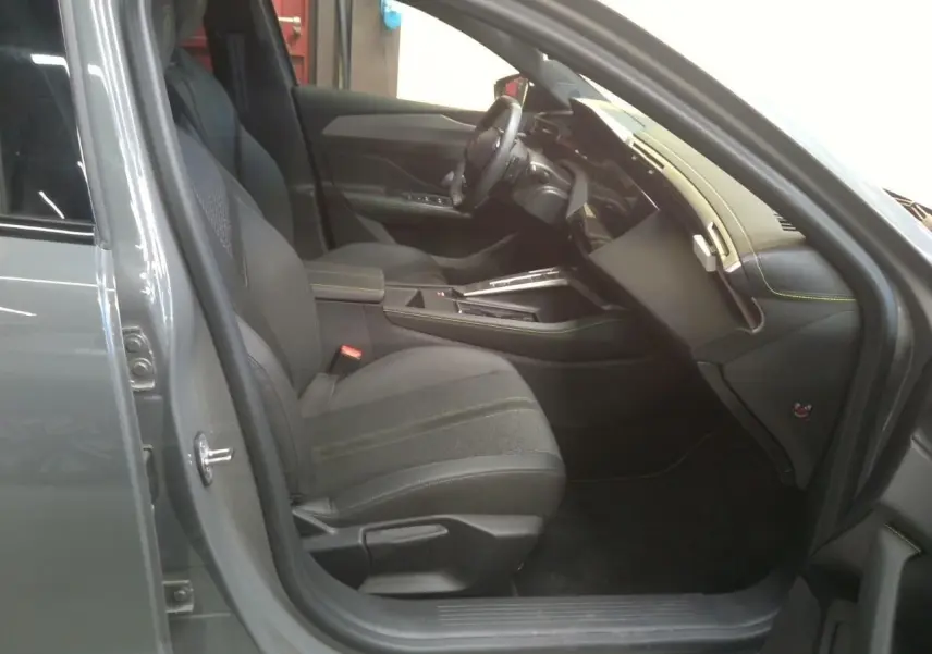 Vue intérieure côté conducteur de la Peugeot 408 Hybrid 145 GT gris selenium, avec sièges noirs et tableau de bord moderne.