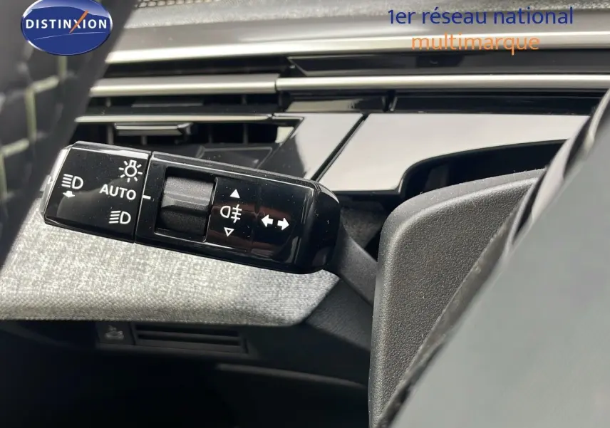 Gros plan sur la commande des feux et clignotants à gauche du volant dans un Peugeot 5008 gris 2025 avec intérieur noir et tissu gris.