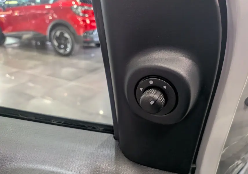 Gros plan sur le réglage électrique des rétroviseurs côté gauche d'une Fiat Panda 2025 blanc Gelato.