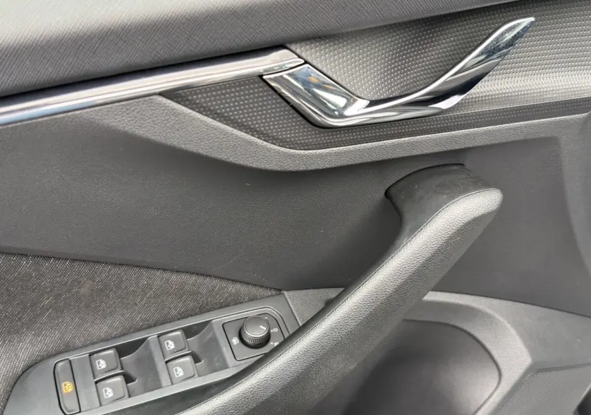 Détail de la porte côté conducteur du Skoda Kamiq gris foncé, avec commandes électriques des vitres et poignée noire.