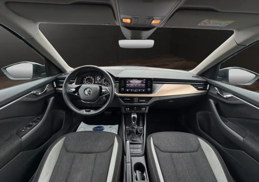 Vue intérieure avant du Skoda Kamiq 2023, tableau de bord clair avec écran tactile et sièges bi-ton gris foncé et clair.