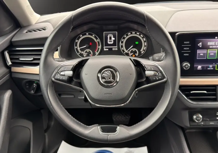 Vue centrée sur le volant cuir noir et le combiné d'instruments numérique du Skoda Kamiq 2023, tableau de bord bois clair.