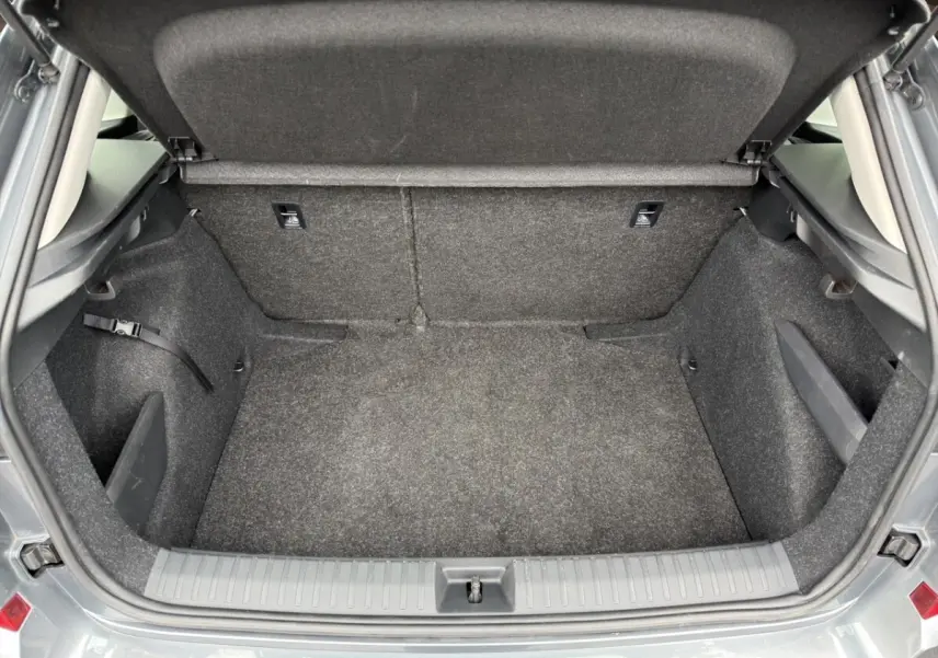 Coffre ouvert du Skoda Kamiq gris foncé 2023, vue intérieure montrant l'espace de rangement vide et tapis gris.