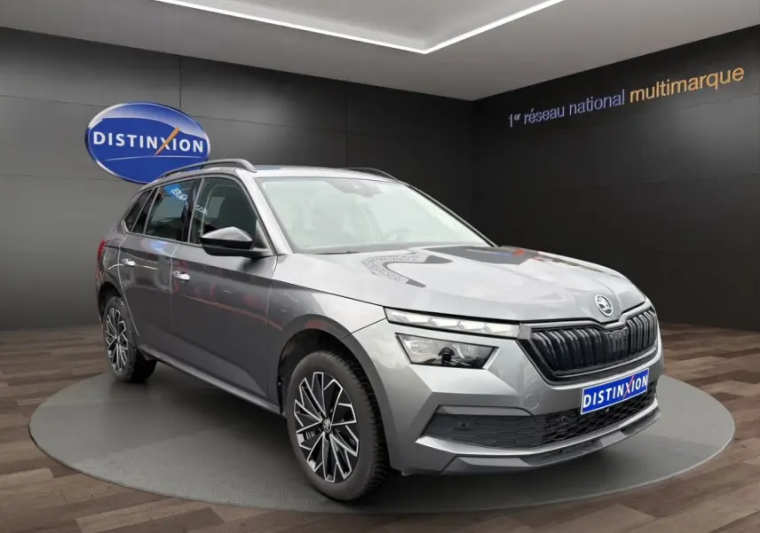 Vue 3/4 avant droite d'un Skoda Kamiq gris foncé avec jantes bi-ton et calandre noire en showroom.