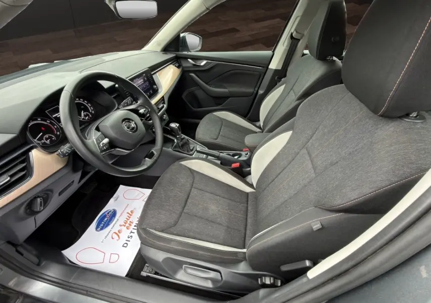 Vue intérieure côté conducteur du Skoda Kamiq 2023 gris foncé, avec sièges tissu bicolore et tableau de bord clair.